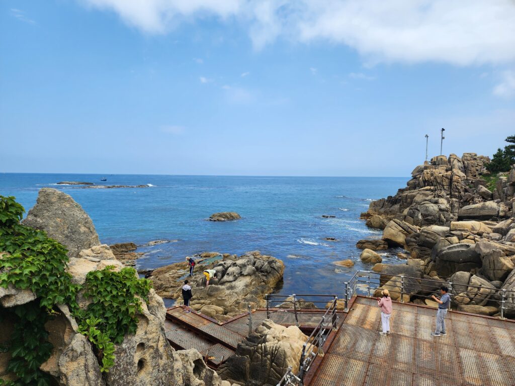 Travelers walking on the wooden boardwalk trail along the ocean at Neungpadae Goseong.