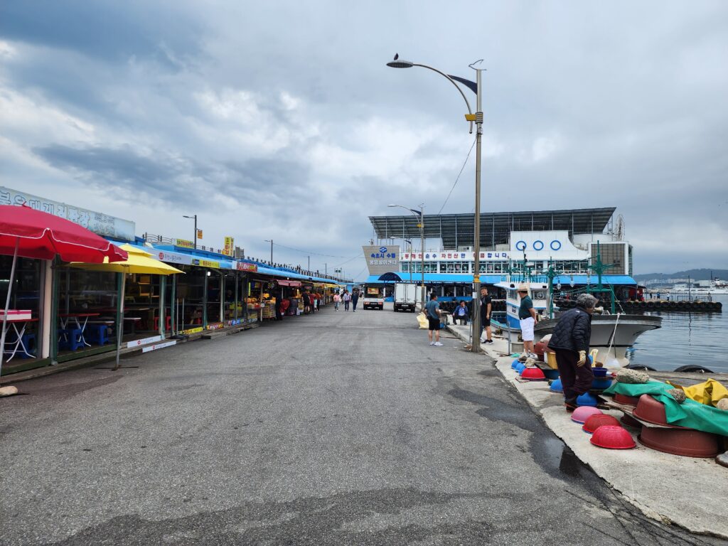 The quiet coastal street and local seafood restaurants lined up along the harbor near Neungpadae in Goseong.