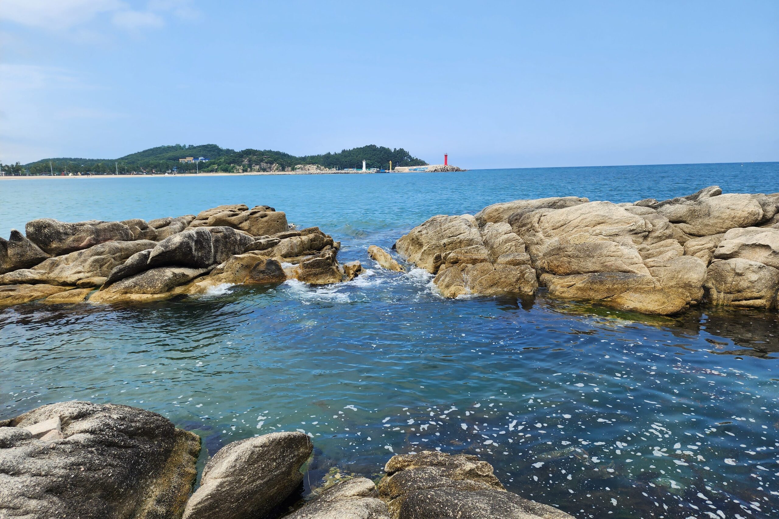 Clear ocean water rushing through coastal granite rocks at Goseong Neungpadae.