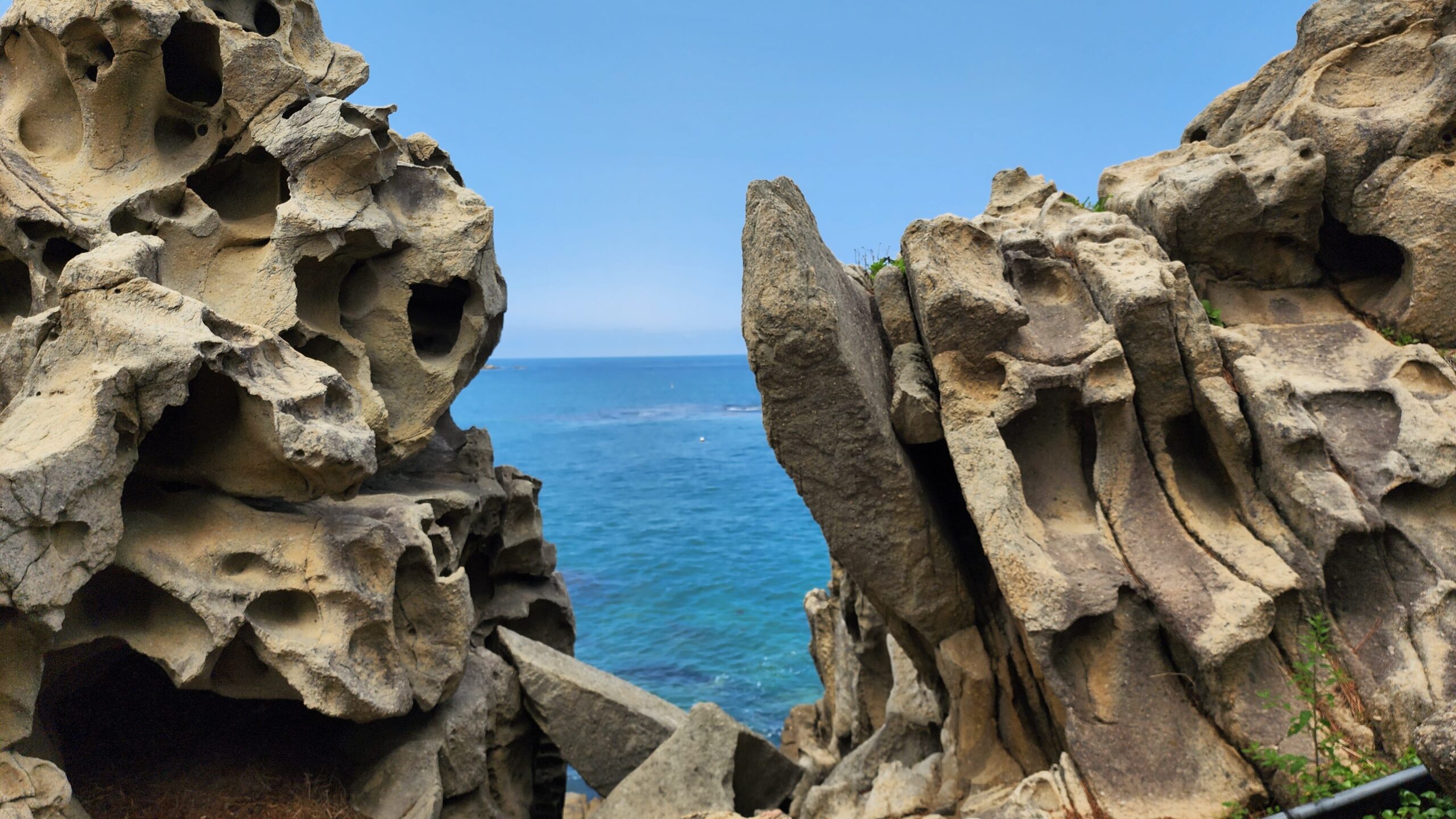 Unique honeycomb rock formation at Goseong Neungpadae Geopark framing a view of the blue ocean.