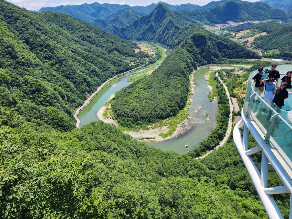 High-angle panoramic view of a horseshoe-shaped river loop surrounded by lush green mountains in Taebaek.