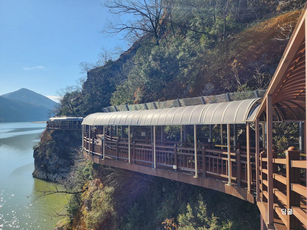The covered wooden walkway of the Danyang River Trail hugging the rocky cliff face.