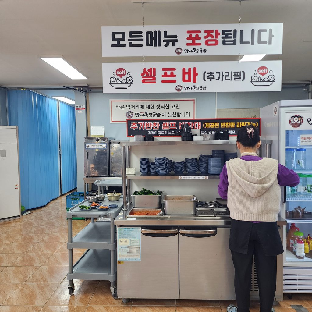 Korean restaurant signs in Korean pointing to a self-service station for side dishes (banchan) and water.